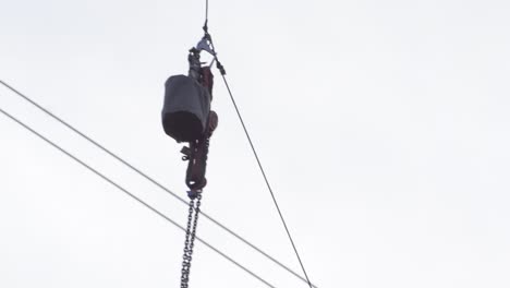 Tools-are-hoisted-up-on-cable-to-electrical-maintenance-technician-on-pylon