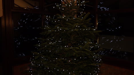 Weihnachtsbaum-In-Der-Nacht-Mit-LED-Lichterketten,-Die-Sich-Auf-Den-Fenstern-Im-Hintergrund-Widerspiegeln