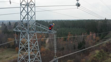 Engineer-working-high-up-on-pylon,-hoisting-equipment-up
