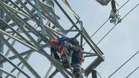 Electrician-works-at-dangerous-height,-climbs-high-voltage-power-line-for-maintenance