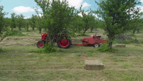 A-farmer-driving-a-hay-baler-between-trees-in-a-field