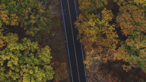 Drone-flying-over-two-lane-highway-in-New-England-in-the-fall-with-leaves-changing-colors-2