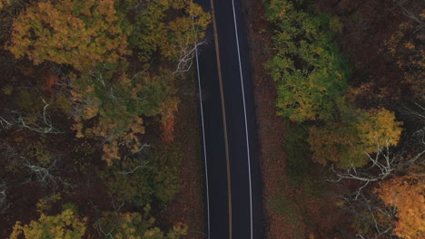 Drone-flying-over-two-lane-highway-in-New-England-in-the-fall-with-leaves-changing-colors-5