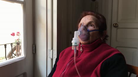 Anciana-Caucásica-Inhalando-Niebla-De-Medicación-Del-Tratamiento-Con-Nebulizador-Junto-A-Una-Ventana-En-Casa