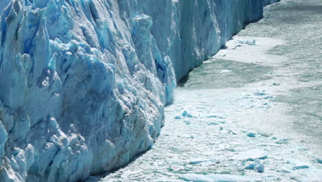 Blue-glacier-melting-with-pieces-of-ice-calving-off,-zoom-in