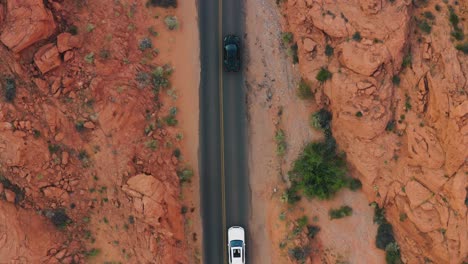 Aerial-birds-eye-view-of-two-luxury-cars-driving-through-the-Valley-of-Fire,-Nevada