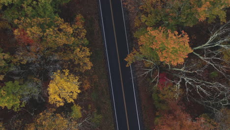 Drone-flying-over-two-lane-highway-in-New-England-in-the-fall-with-leaves-changing-colors-3