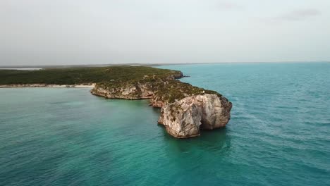 Person-standing-at-the-end-of-a-rocky-cliff-on-the-ocean-in-Providenciales-in-the-Turks-and-Caicos-archipelago