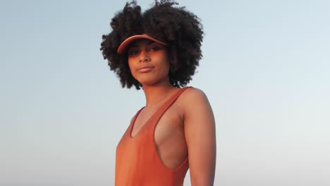 Girl-with-curly-afro-hair-posing-in-an-orange-swimsuit
