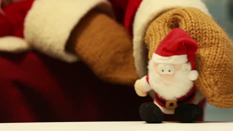 Weihnachtsvater-Nahm-Einen-Spielzeugweihnachtsmann-Von-Einem-Tisch-In-Die-Hand