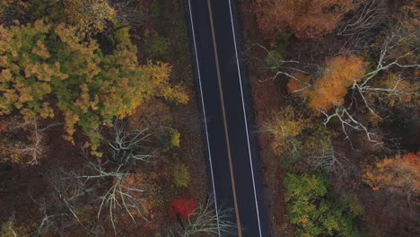 Drone-flying-over-two-lane-highway-in-New-England-in-the-fall-with-leaves-changing-colors-4