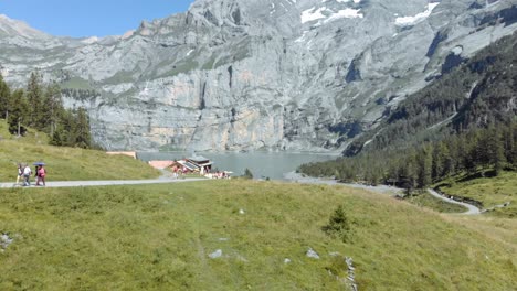 Really-Beautiful-And-Amazing-View-Arial-Reveal-Shoot-Passing-Over-Head-of-Turquoise-Oeschinen-Lake-With-Rocky-Cliffs-in-The-Valley-Under-Alpine-mountains-Oberland,-Switzerland