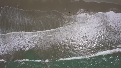 Cenital-drone-shot-flying-straight-down-over-the-splashing-waves-at-the-beach-in-Playas-General-Villamil,-Ecuador