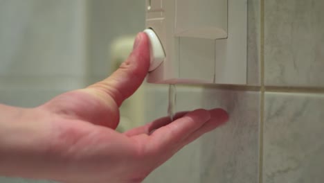 Close-up-of-male-hand-getting-dose-of-liquid-soap-out-of-a-soap-dispenser-in-the-bathroom