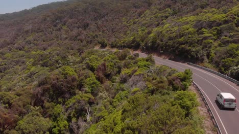 Drone-aerial-following-van-driving-down-scenic-coastal-road