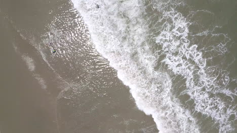Cenital-drone-shot-flying-straight-over-the-splashing-waves-at-the-beach-in-Playas-General-Villamil,-Ecuador