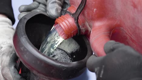 Pouring-fuel-gas-into-the-tank-of-race-car-from-fuel-pot-by-two-men-mechanics-in-slow-motion