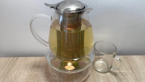 Moderne-Teekanne-Aus-Transparentem-Glas-Mit-Kerzenwärmer-Und-Teetasse,-Vorderansicht