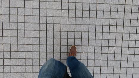 A-Man-Dressed-in-Jeans-And-Wearing-Brown-Shoes-Walks-Through-a-Granite-Pavement