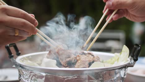 Using-chopsticks-for-BBQ-grilled-pork-or-Moo-Kra-ta
