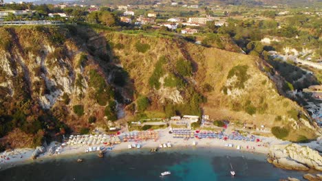 Aerial-view-away-from-a-beach-at-Cabo-Vaticano,-during-golden-hour,-in-Calabria,-South-Italy---Pull-back,-drone-shot