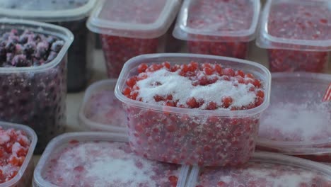 Esslöffel-Zucker-Auf-Rote-Johannisbeerbeeren-In-Plastikbehältern-Gestreut