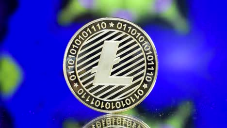 Close-Up-Of-Single-Golden-Litecoin-On-A-Mirroring-Ground-With-Colourful-Hypnotic-Background