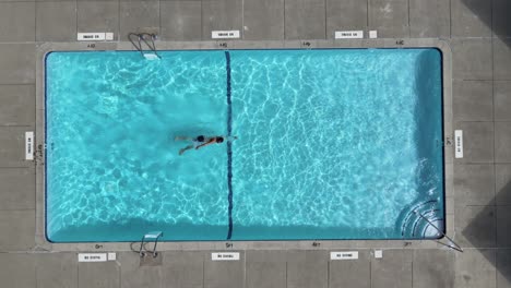 Top-view-of-a-man-Swimming-from-one-side-of-a-inground-backyard-pool-to-the-other-and-back