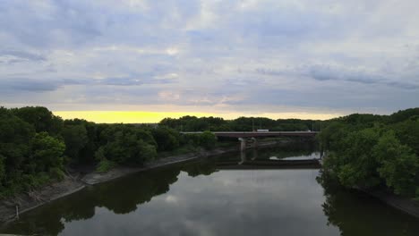 Während-Die-Sonnenuntergänge-über-Der-Autobahnbrücke-Einen-Fluss-überqueren,-Der-Den-Mississippi-Südlich-Der-Partnerstädte-In-Minnesota-Speist,-Spiegelt-Sich-Die-Küstenlinie-Im-Stillen-Wasser