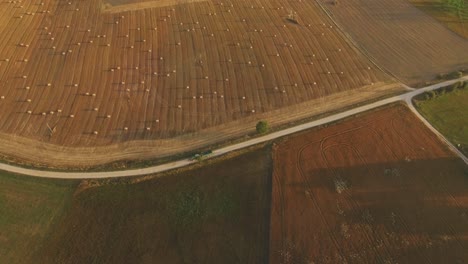 Tractor-Con-Remolque-Conduce-A-Través-De-Un-Camino-Rural-De-Grava-Que-Atraviesa-Campos-Agrícolas-En-Una-Noche-De-Verano