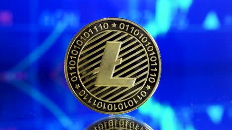 Close-Up-Of-Single-Golden-Litecoin-On-A-Mirroring-Ground-With-Symolization-Of-Rising-Stock-In-The-Background
