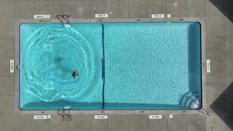 Eine-Ansicht-Von-Oben-Nach-Unten-Eines-Mannes,-Der-In-Einen-Pool-Im-Hinterhof-Springt-Und-Schwimmt