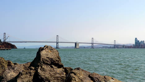 Still-shot-of-the-San-Francisco-Bay-Bridge-in-the-North-Bay-as-seen-from-the-rocks-on-Treasure-Island