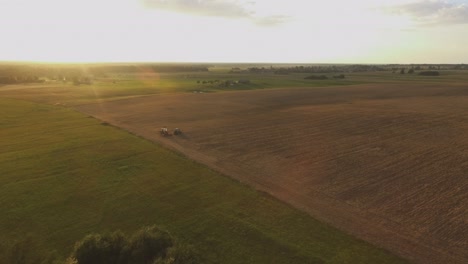 Schwere-Landmaschinentraktoren-Mit-Geräten-Auf-Landwirtschaftlichen-Feldern-An-Einem-Sonnigen-Sommerabend