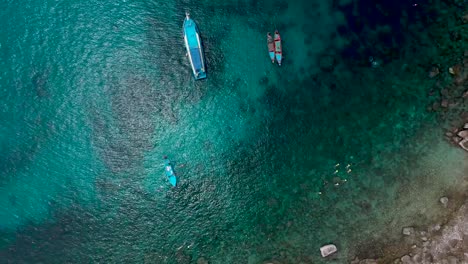 Drone-Aerial-birds-eye-view-of-coastal-shore-with-rocky-bay,-longtails-and-coral-reef