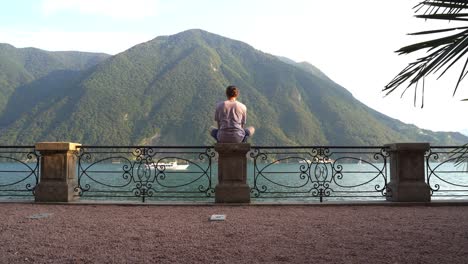 Guy-meditating-on-the-lake-with-beautiful-mountains-and-landscape