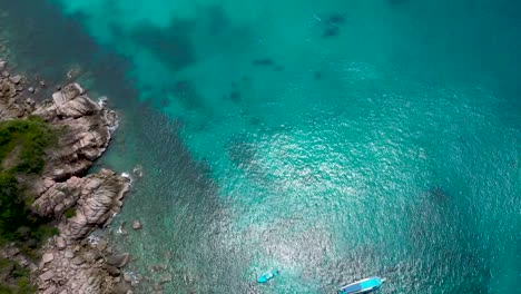 Drone-aerial-shot-from-rocky-bay-tilting-up-to-horizon-in-Koh-Tao,-Thailand