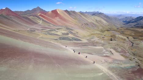 Aerial-View-Of-Hikers-Trekking-Alongside-Rainbow-Mountain-In-The-Andes-Of-Peru