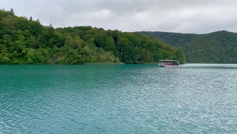 Drohnentiefflug-über-Dem-Azurblauen-Wasser-Der-Plitvicer-Seen,-Vorbei-An-Einem-Schönen-Boot,-4k
