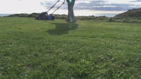 A-Man-With-A-Self-Propelled-Trimmer-Cuts-Grass-In-A-Lawn-Near-The-Sea-4