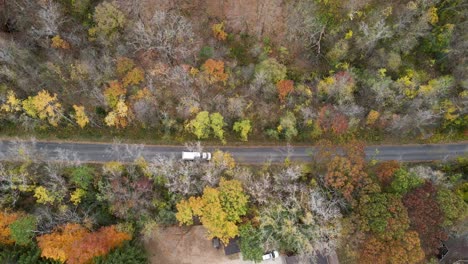 Top-down-view-of-a-white-garbage-truck-driving-on-the-road-through-the-forest-in-La-Crosse,-Wisconsin