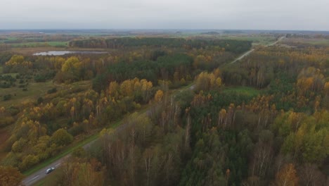 Tractor-Drives-on-a-Regional-Road-Leading-Through-the-Autumn-Forest
