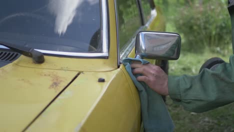 A-Man-Cleans-A-Polished-Yellow-Vintage-Car-Side-Mirror