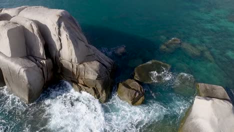 Slow-motion-Aerial-Flying-Over-Waves-Breaking-On-Rocks-clear-water