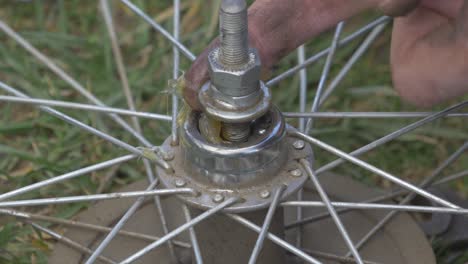 A-Man-Applyes-Fatty-Grease-to-the-Axle-of-a-Bicycle-Wheel-with-his-Fingers