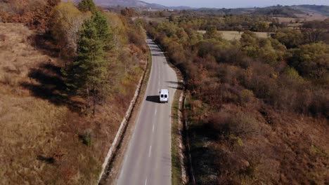 Following-A-White-Van-Driving-On-Autumn-Color-Road-On-A-Sunny-Day---Aerial-Drone-Shot
