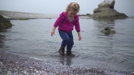 Adorable-Little-Girl-At-The-Seashore-Playing-Water-With-Her-Hands-And-Feet-Then-Walks-Away---Medium-Shot