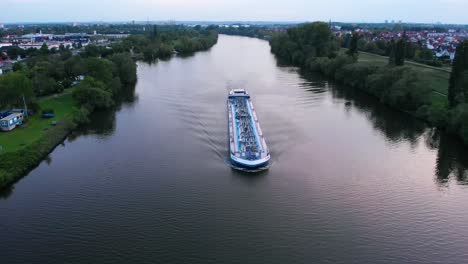 Aerial-view-of-a-transport-ferry-on-the-Main-river,-sunny-evening,-in-Raunheim,-Germany---reverse-drone-shot
