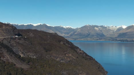 Drone-reveal-of-mountain-surrounded-lake-in-Queenstown-New-Zealand