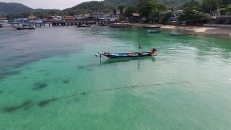 Flying-around-longtail-boat-in-the-middle-of-water-island-background